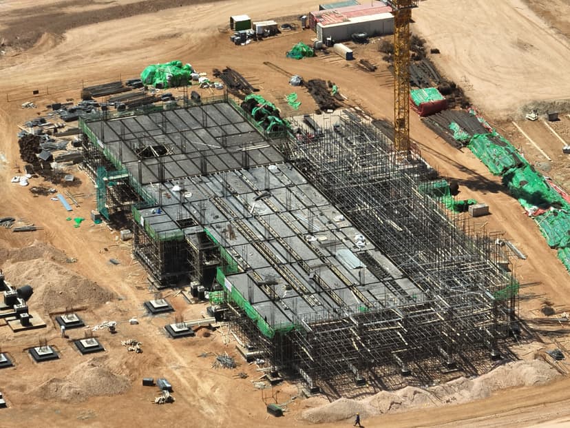 Aerial view of scaffolding and formwork for a rectangular industrial building under construction at the Benghazi steel plant.